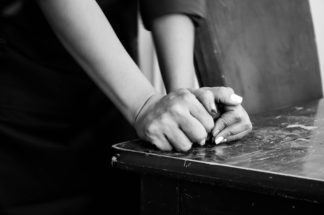 Hands examining printed black and white documentary photographs on a table