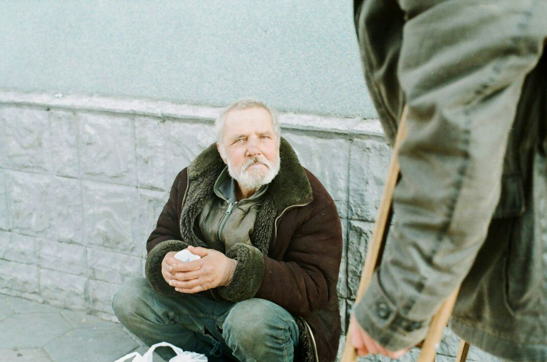 Photographer interviewing an elderly Polish man in his home with a notebook and camera
